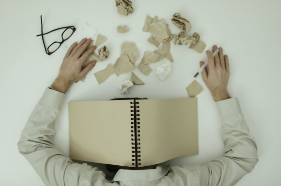 Une personne épuisée endormie sur son bureau avec un livre sur la tête, illustrant le coup de fatigue après le repas et le besoin de naturopathie