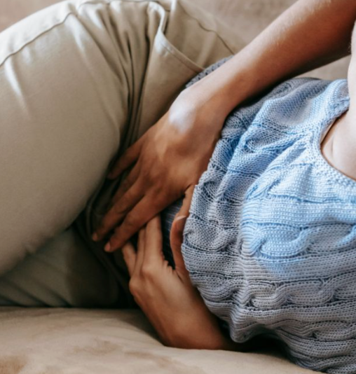Une femme allongée se tenant le ventre de douleur, illustrant l'inconfort lié aux problèmes digestifs chroniques.